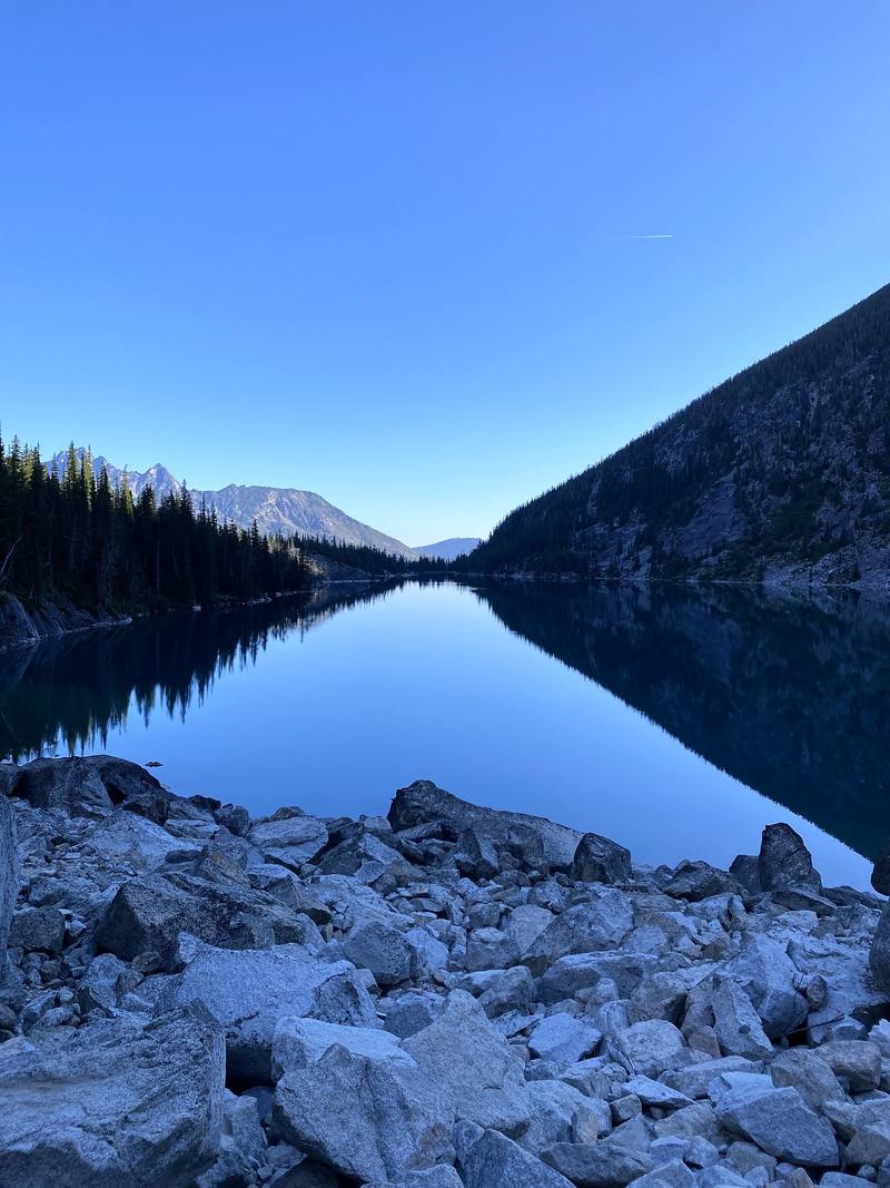 Colchuck Lake, still and clear, from the boulders at its far end.