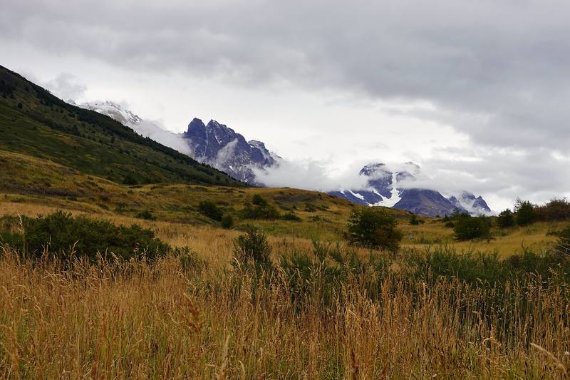 Open grassland on the first day, the Paine peaks in the cloud ahead.