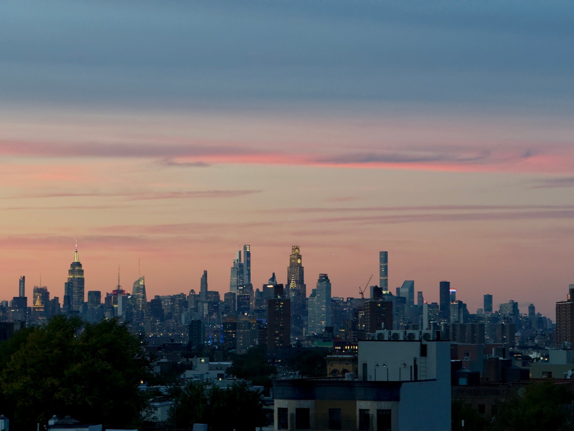 The Manhattan skyline at dusk under a pink sky