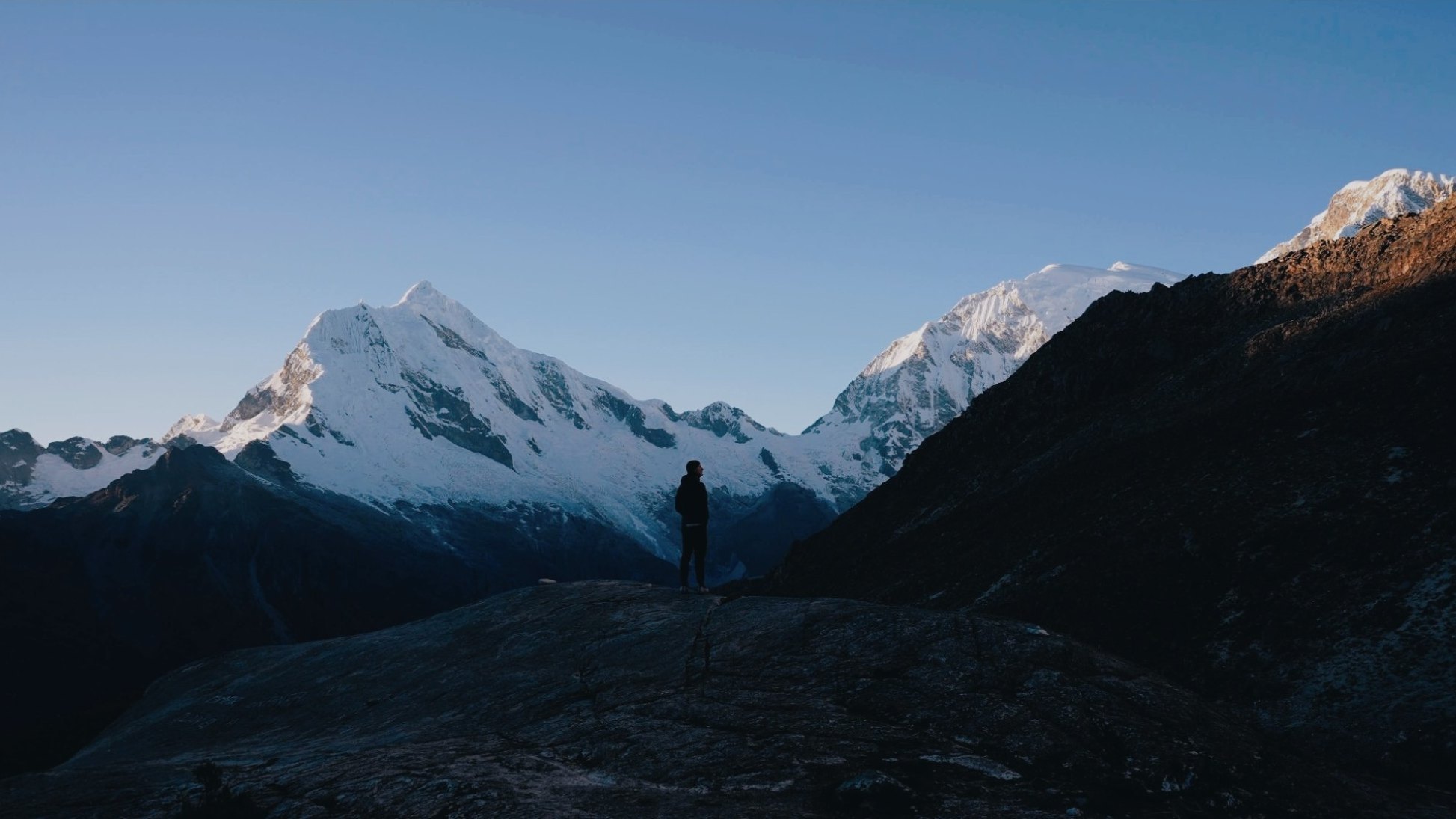 Kraig standing below snowy peaks at sunrise
