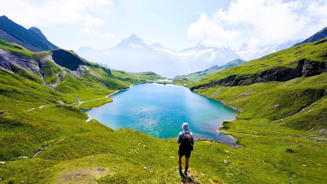 A hiker overlooking a turquoise mountain lake.